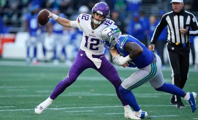 Minnesota Vikings quarterback Max Brosmer (12) passes an interception against Seattle Seahawks defensive end DeMarcus Lawrence (0) during the first half of an NFL football game Sunday, Nov. 30, 2025, in Seattle. (AP Photo/Stephen Brashear)