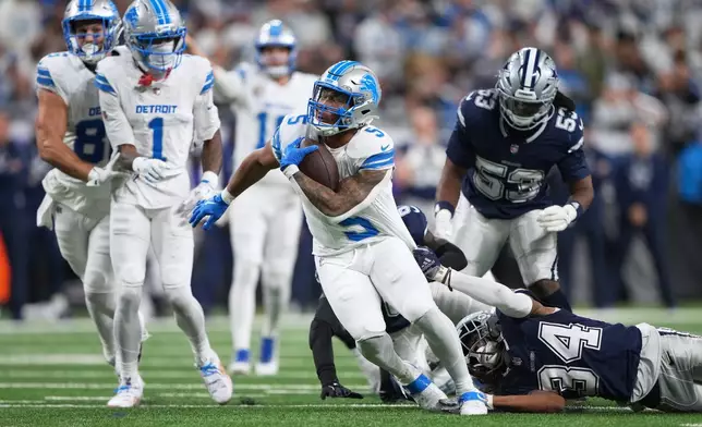 Detroit Lions running back David Montgomery (5) runs for a touchdown while Dallas Cowboys running back Malik Davis (34) tries to stop him during the first half of an NFL football game Thursday, Dec. 4, 2025, in Detroit. (AP Photo/Ryan Sun)