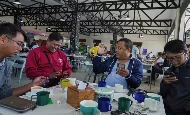 People use their mobile phones at a tea shop in Naypyitaw, Myanmar, Monday, Dec. 1, 2025. (AP Photo/Aung Shine Oo)