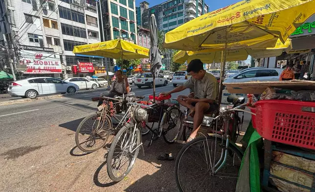 A man uses a mobile phone as he waits for passengers on his trishaw in Yangon, Myanmar Monday, Dec. 1, 2025. (AP Photo/Thein Zaw)