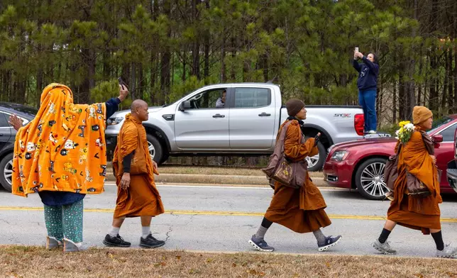 Supporters watch Buddhist monks on a "Walk for Peace" on Veterans Parkway in Fayetteville, Ga., on Monday, Dec. 29, 2025, from Texas to Washington, D.C. (Arvin Temkar/Atlanta Journal-Constitution via AP)