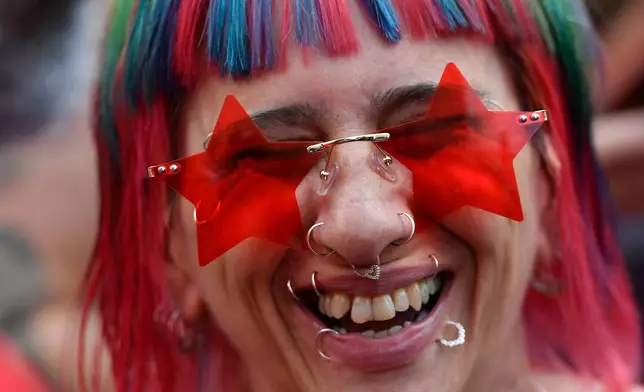 FILE - A woman wearing star-shaped glasses smiles during a campaign rally for former President Luiz Inacio Lula da Silva in Sao Paulo, Brazil, Oct. 29, 2022. (AP Photo/Matias Delacroix, File)
