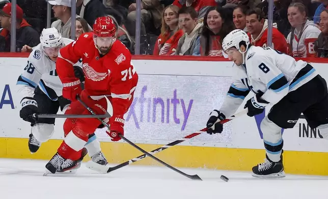 Detroit Red Wings center Dylan Larkin (71) is defended by Utah Mammoth defenseman Nate Schmidt (88) and center Nick Schmaltz (8) during the first period of an NHL hockey game Wednesday, Dec. 17, 2025, in Detroit. (AP Photo/Duane Burleson)
