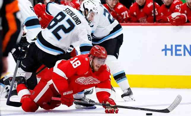 Utah Mammoth center Kevin Stenlund (82) lands on top of Detroit Red Wings center Andrew Copp (18) while they chase a loose puck during the second period of an NHL hockey game Wednesday, Dec. 17, 2025, in Detroit. (AP Photo/Duane Burleson)
