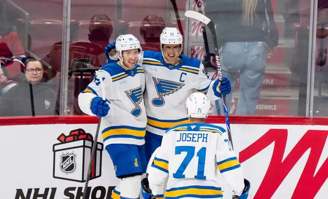 St. Louis Blues' Dylan Holloway (81) celebrates after his goal with teammates Brayden Schenn (10) and Mathieu Joseph (71) during second-period NHL hockey game action against the Montreal Canadiens in Montreal, Sunday, Dec. 7, 2025. (Christopher Katsarov/The Canadian Press via AP)