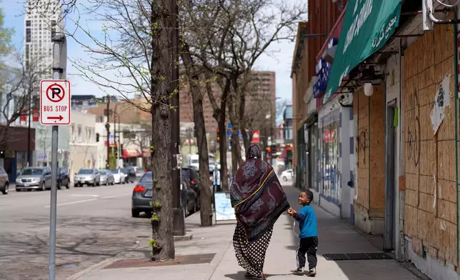 FILE - A woman and a child hold hands as they walk down a street in the predominantly Somali neighborhood of Cedar-Riverside in Minneapolis on Thursday, May 12, 2022. (AP Photo/Jessie Wardarski, File)