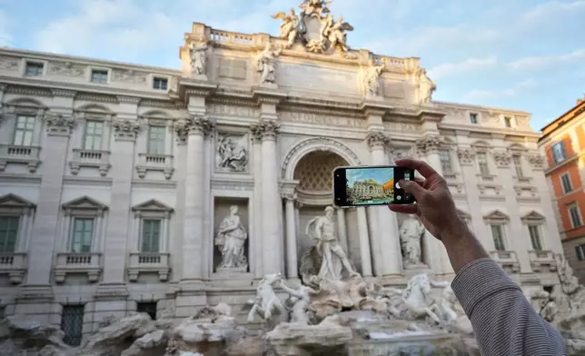 A visitor takes a photo of Rome's Trevi Fountain, Friday, Dec. 19, 2025, as the city municipality announced that, starting on Feb. 1, it will impose a 2 euro fee for tourists to visit the recessed fountain edge. (AP Photo/Andrew Medichini)