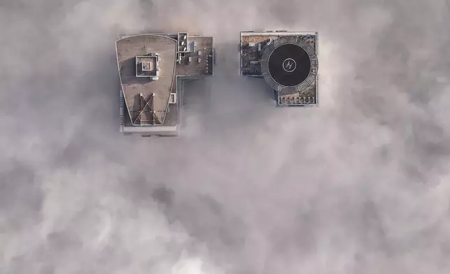 An aerial view of buildings peaking through a dense layer of fog in Sarajevo, Bosnia, Thursday, Dec. 18, 2025. (AP Photo/Armin Durgut)