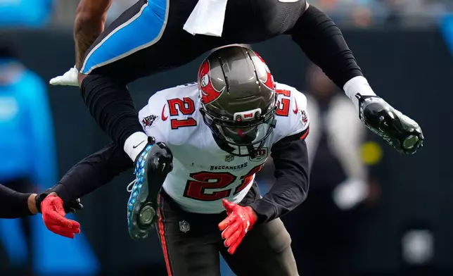 Carolina Panthers tight end Ja'Tavion Sanders leaps over Tampa Bay Buccaneers cornerback Benjamin Morrison during the first half of an NFL football game, Sunday, Dec. 21, 2025, in Charlotte, N.C. (AP Photo/Erik Verduzco)