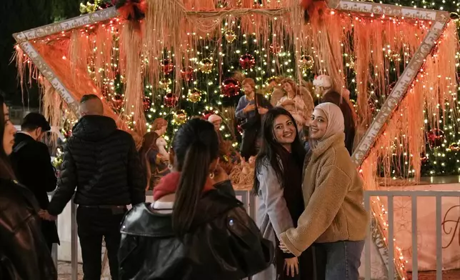People pose for a picture in Manger Square in the West Bank city of Bethlehem, Tuesday, Dec. 16, 2025. (AP Photo/Mahmoud Illean)