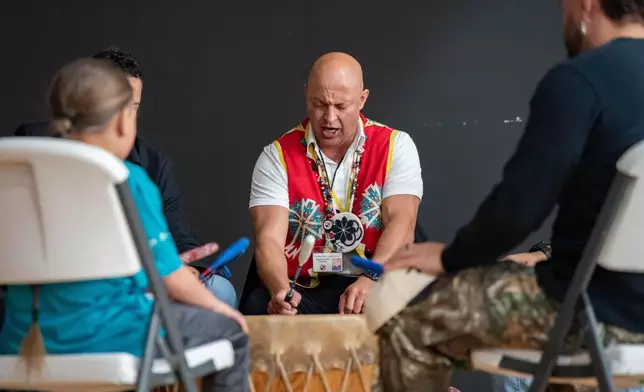People sing while playing drums during a watch party hosted by the Lumbee Tribe of North Carolina, Wednesday, Dec. 17, 2025, in Pembroke, N.C. (AP Photo/Allison Joyce)