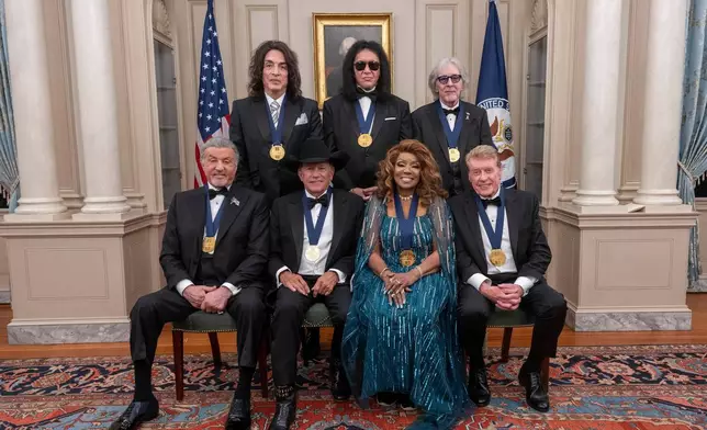 The 2025 Kennedy Center Honorees, front row from left, Sylvester Stallone, George Strait, Gloria Gaynor and Michael Crawford; back row from left, members of the rock band KISS, Paul Stanley, Gene Simmons and Peter Criss, pose for a group photo at the 48th Kennedy Center Honors Medallion Reception, hosted at the U.S. Department of State, Saturday, Dec. 6, 2025 in Washington. (AP Photo/Kevin Wolf)