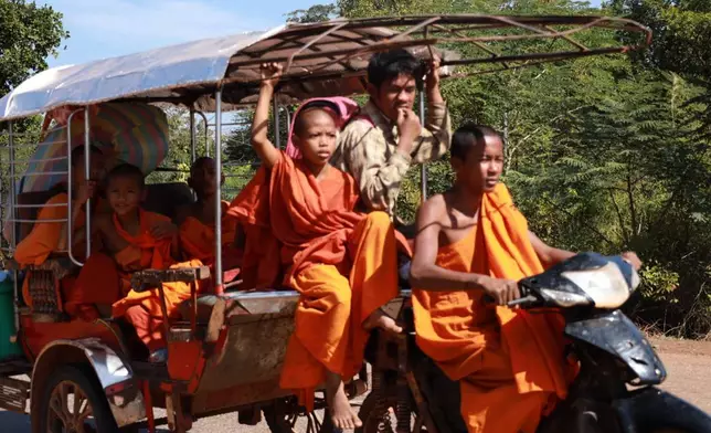 In this photo released by Agence Kampuchea Press (AKP), Cambodian Buddhist monks sit on a motor cart as they flee from their pagoda of Preah Vihear province, near the border with Thailand, Monday, Dec. 8, 2025. (AKP via AP)