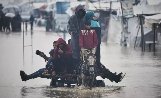Palestinians cross a flooded street following heavy rain in Khan Younis, southern Gaza Strip, Thursday, Dec. 11, 2025. (AP Photo/Abdel Kareem Hana)