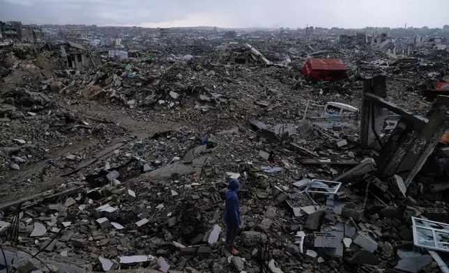 A man walks through the rubble amid stormy weather in Gaza City Thursday, Dec. 11, 2025. (AP Photo/Jehad Alshrafi)