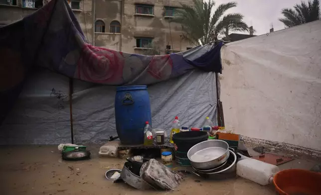 Pans, bowls, and other utensils are seen in a flooded area where Lamia Abdel Dayem lives in a temporary tent camp for displaced Palestinians after heavy rainfall in Deir al-Balah, central Gaza Strip, Friday, Dec. 12, 2025. (AP Photo/Abdel Kareem Hana)