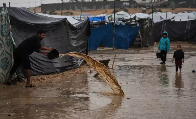 A man clears water from his tent at a camp for displaced Palestinians following heavy rain in Deir al-Balah, Gaza Strip, Thursday, Dec. 11, 2025. (AP Photo/Abdel Kareem Hana)
