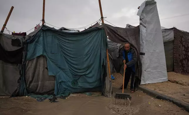 Hosni Abu Reda clears water from his tent at a camp for displaced Palestinians following heavy rain in Khan Younis, southern Gaza Strip, Thursday, Dec. 11, 2025. (AP Photo/Abdel Kareem Hana)