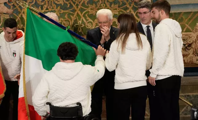 Italian athletes Rene' De Silvestro, left and Chiara Mazzel receive the Italian flag from Italian President Sergio Mattarella for the Milan-Cortina Winter Olympic games, at the Quirinale Presidential palace, in Rome, Monday, Dec. 22, 2025. (AP Photo/Gregorio Borgia)