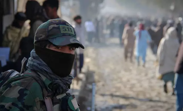 A Taliban policeman looks on as a crowd heads toward a stadium to attend the public execution carried out by Taliban authorities of a man sentenced by the Supreme Court for killing 13 members of a family, including children, earlier this year, in the eastern city of Khost, Afghanistan, Tuesday, Dec. 2, 2025. (AP Photo/Saifullah Zahir)