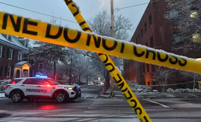 A police vehicle rests at an intersection near crime scene tape at Brown University, Sunday, Dec. 14, 2025, in Providence, R.I., following a Saturday, Dec. 13, 2025 shooting at the university. (AP Photo/Steven Senne)