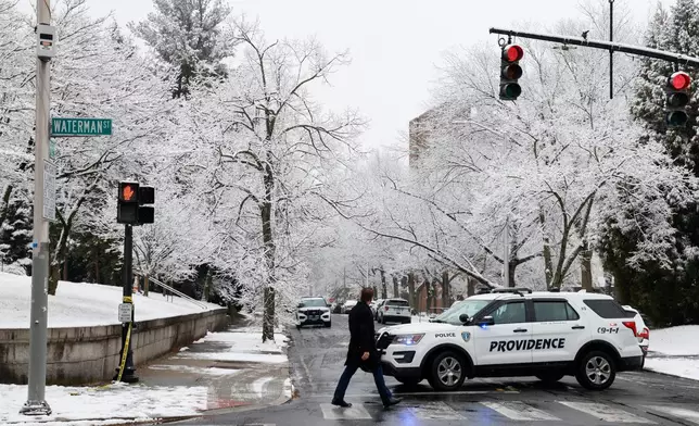 A pedestrian walks across the intersection of Waterman St. and Hope St. Sunday, Dec. 14, 2025, after a shooting on Saturday in Providence, R.I. (Lily Speredelozzi/The Sun Chronicle via AP)
