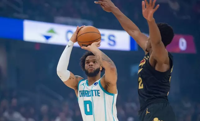 Charlotte Hornets' Miles Bridges (0) shoots as Cleveland Cavaliers' De'Andre Hunter, right, defends during the first half of an NBA basketball game in Cleveland, Sunday, Dec. 14, 2025. (AP Photo/Phil Long)
