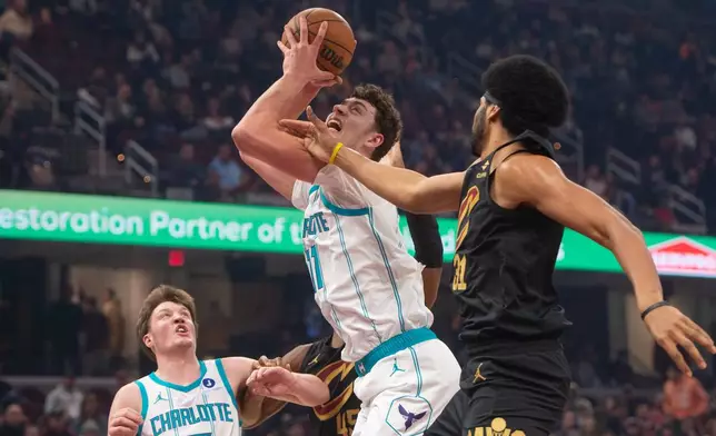 Charlotte Hornets' Ryan Kalkbrenner, center, grabs a rebound in front of Cleveland Cavaliers' Jarrett Allen, right, as Hornets' Kon Knueppel, left, watches during the first half of an NBA basketball game in Cleveland, Sunday, Dec. 14, 2025. (AP Photo/Phil Long)