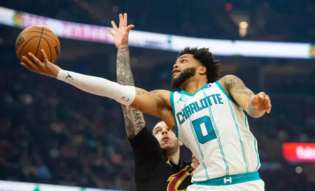Charlotte Hornets' Miles Bridges (0) shoots as Cleveland Cavaliers' Lonzo Ball, left, defends during the first half of an NBA basketball game in Cleveland, Sunday, Dec. 14, 2025. (AP Photo/Phil Long)