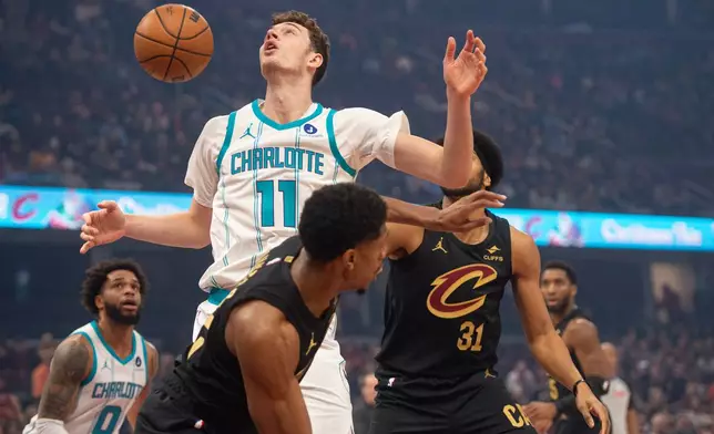 Charlotte Hornets' Ryan Kalkbrenner (11) cannot control the ball as Cleveland Cavaliers' De'Andre Hunter, front, and Jarrett Allen (31) defend during the first half of an NBA basketball game in Cleveland, Sunday, Dec. 14, 2025. (AP Photo/Phil Long)
