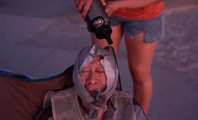 FILE - Grace Chyuwei pours water on Joe Chyuwei to help with the heat Aug. 3, 2025, in Death Valley National Park, Calif. (AP Photo/John Locher, File)