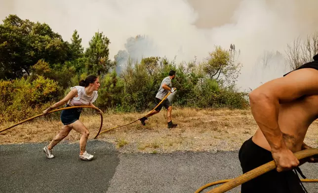 FILE - Local residents and volunteers work together to battle an encroaching wildfire in Larouco, northwestern Spain, Aug. 13, 2025. (AP Photo/Lalo R. Villar, File)