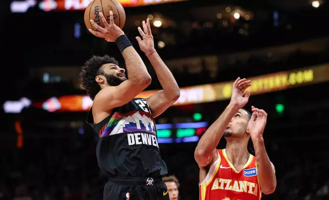 Denver Nuggets guard Jamal Murray, left, shoots against Atlanta Hawks forward Zaccharie Risacher during the first half of an NBA basketball game, Friday, Dec. 5, 2025, in Atlanta. (AP Photo/Colin Hubbard)