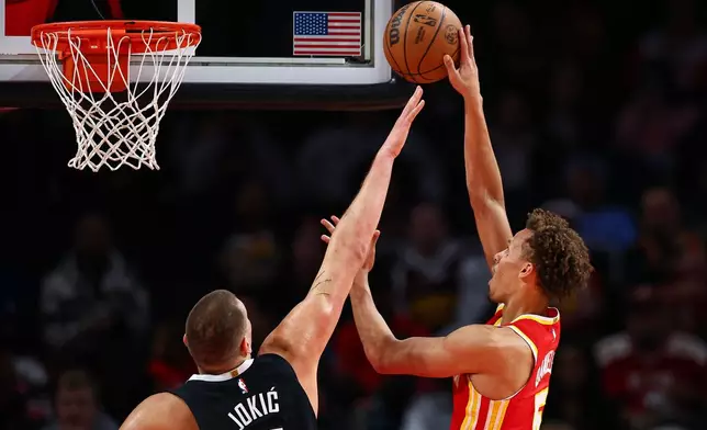 Atlanta Hawks guard Dyson Daniels, right, shoots the ball over Denver Nuggets center Nikola Jokic during the first half of an NBA basketball game, Friday, Dec. 5, 2025, in Atlanta. (AP Photo/Colin Hubbard)