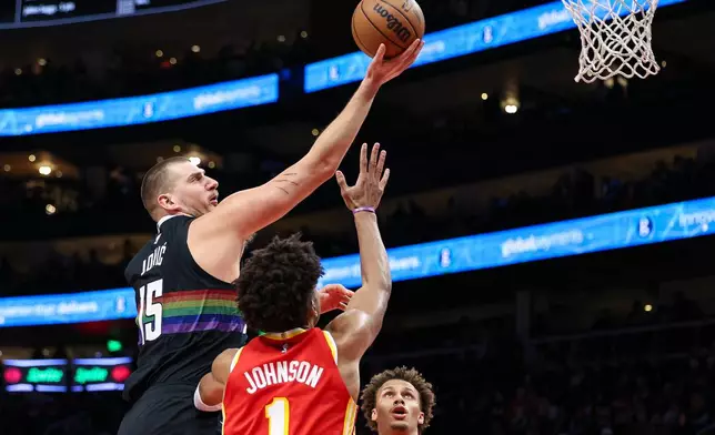 Denver Nuggets center Nikola Jokic, left, shoots the ball over Atlanta Hawks forward Jalen Johnson (1) during the first half of an NBA basketball game, Friday, Dec. 5, 2025, in Atlanta. (AP Photo/Colin Hubbard)