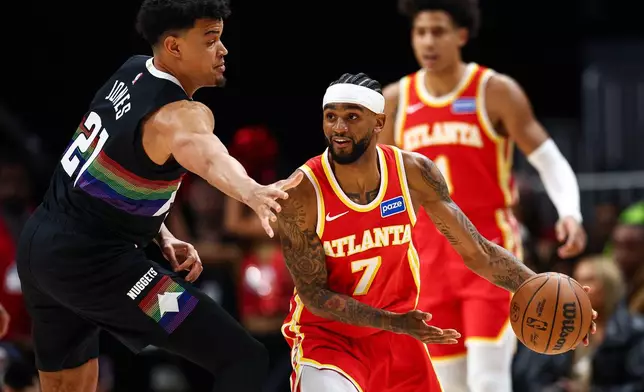 Atlanta Hawks guard Nickeil Alexander-Walker (7) looks to pass the ball defended by Denver Nuggets forward Spencer Jones, left, during the first half of an NBA basketball game, Friday, Dec. 5, 2025, in Atlanta. (AP Photo/Colin Hubbard)