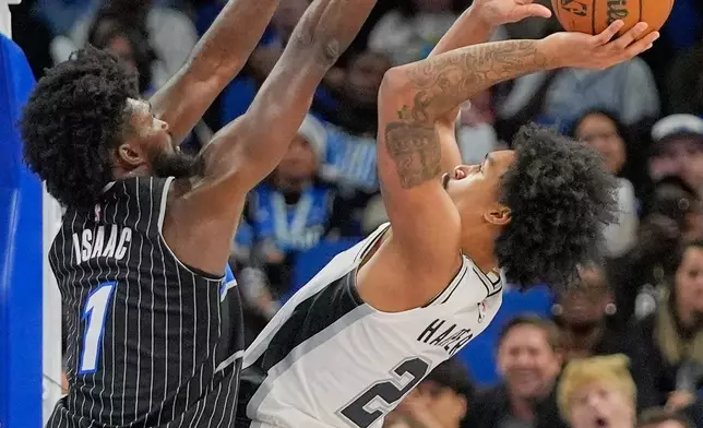 San Antonio Spurs guard Dylan Harper, right, shoots over Orlando Magic forward Jonathan Isaac (1) during the second half of an NBA basketball game, Wednesday, Dec. 3, 2025, in Orlando, Fla. (AP Photo/John Raoux)