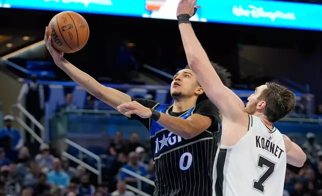 Orlando Magic guard Anthony Black (0) gets past center Luke Kornet (7) for a shot during the second half of an NBA basketball game, Wednesday, Dec. 3, 2025, in Orlando, Fla. (AP Photo/John Raoux)