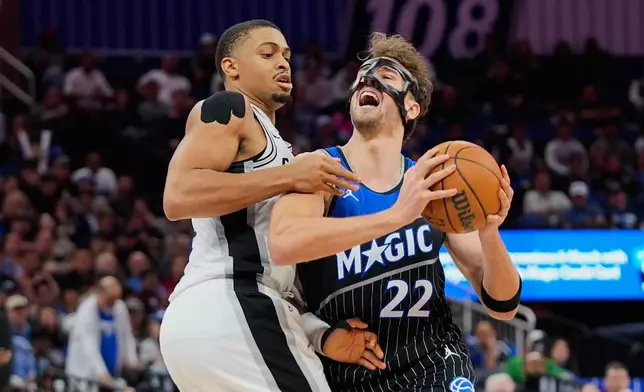 Orlando Magic forward Franz Wagner (22) is fouled by San Antonio Spurs forward Keldon Johnson, left, as he goes up for a shot during the second half of an NBA basketball game, Wednesday, Dec. 3, 2025, in Orlando, Fla. (AP Photo/John Raoux)