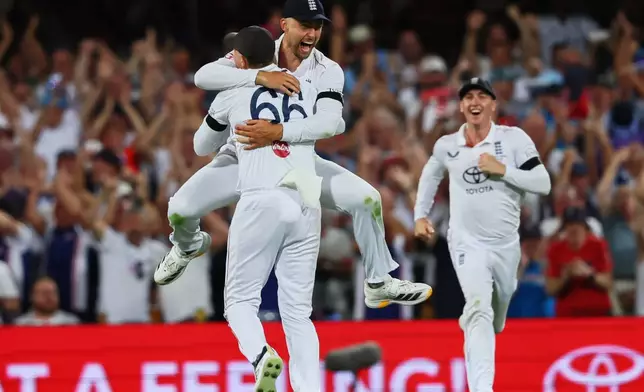 England's Will Jacks jumps to celebrate with teammate England's Joe Root the wicket of Australia's captain Steve Smith during the second Ashes cricket test match between Australia and England in Brisbane, Friday, Dec. 5, 2025.. (AP Photo/Tertius Pickard)