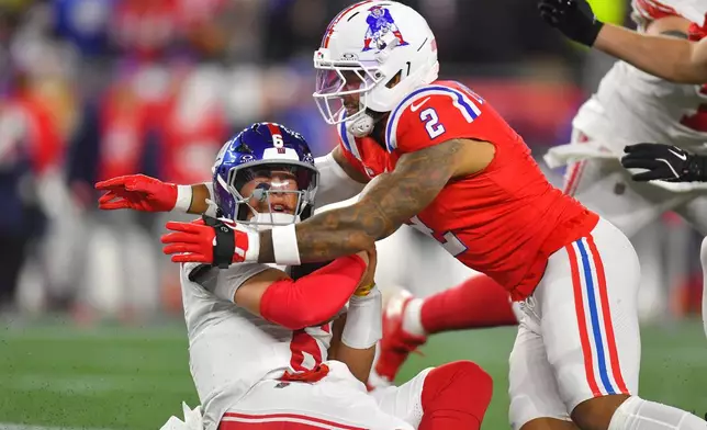 New York Giants quarterback Jaxson Dart, left, is sacked by New England Patriots linebacker Harold Landry III (2) during the first half of an NFL football game, Monday, Dec. 1, 2025, in Foxborough, Mass. (AP Photo/Steven Senne)