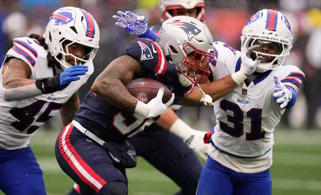 New England Patriots running back Treveyon Henderson, middle, stiff arms Buffalo Bills cornerback Maxwell Hairston (31) during the first half of an NFL football game in Foxborough, Mass., Sunday, Dec. 14, 2025. (AP Photo/Charles Krupa)