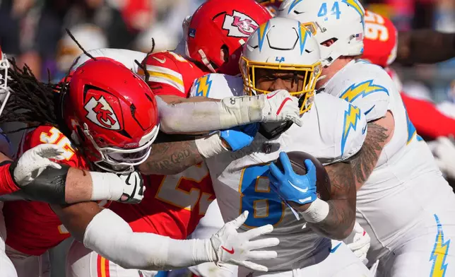 Los Angeles Chargers running back Omarion Hampton (8) is tackled by Kansas City Chiefs linebacker Nick Bolton (32) and linebacker Drue Tranquill during the first half of an NFL football game Sunday, Dec. 14, 2025, in Kansas City, Mo. (AP Photo/Ed Zurga)