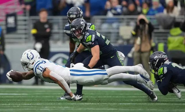 Indianapolis Colts wide receiver Michael Pittman Jr. (11) loses a shoe as he dives for yardage as Seattle Seahawks safety Ty Okada (39) during the first half of an NFL football game Sunday, Dec. 14, 2025, in Seattle. (AP Photo/Lindsey Wasson)