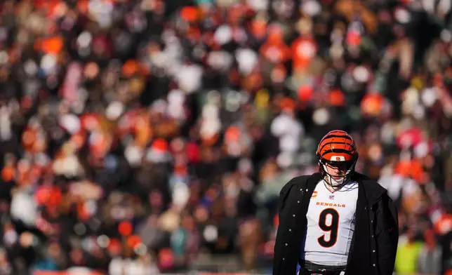 Cincinnati Bengals quarterback Joe Burrow (9) wears a sideline cape during a time out in the first half of an NFL football game against the Baltimore Ravens, Sunday, Dec. 14, 2025, in Cincinnati. (AP Photo/Jeff Dean)
