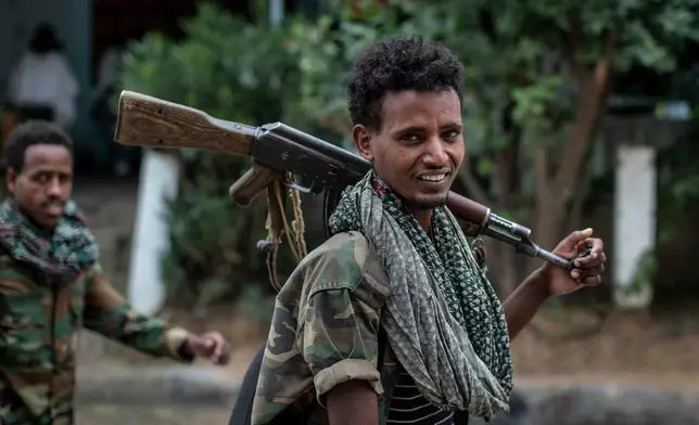 FILE - Fighters loyal to the Tigray People's Liberation Front (TPLF) walk along a street in the town of Hawzen, then controlled by the group, in the Tigray region of northern Ethiopia, May 7, 2021. (AP Photo/Ben Curtis, File)