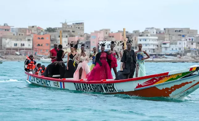 Models present creations in a traditional fishing boat during Dakar Fashion Week in Dakar, Senegal, Saturday, Dec. 6, 2025. (AP Photo/Misper Apawu)
