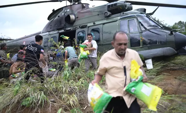 Flood survivors carry relief goods distributed by an Indonesian Air Force helicopter in Central Aceh, Indonesia, Saturday, Dec. 6, 2025. (AP Photo/Reza Saifullah)