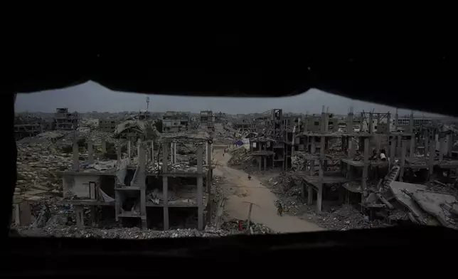 Palestinians walk through the destruction left by the Israeli air and ground offensive in Jabaliya, northern Gaza Strip, Saturday, Dec. 6, 2025. (AP Photo/Abdel Kareem Hana)
