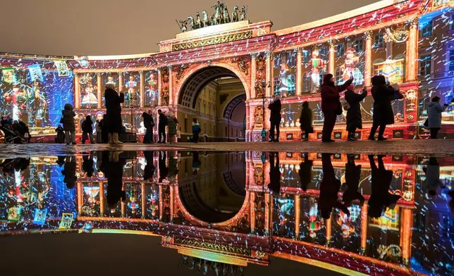 People watch a multimedia light show during the "Country of Light" festival at the Palace Square, in St. Petersburg, Russia, Sunday, Dec. 7, 2025. (AP Photo/Dmitri Lovetsky)